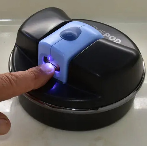 An electric nail clipper inside "the Pod," which stabilizes it on a surface for one-handed use.