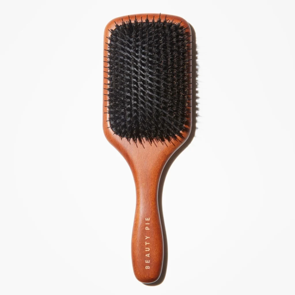A wooden hairbrush with nylon and boar bristles over a white background.