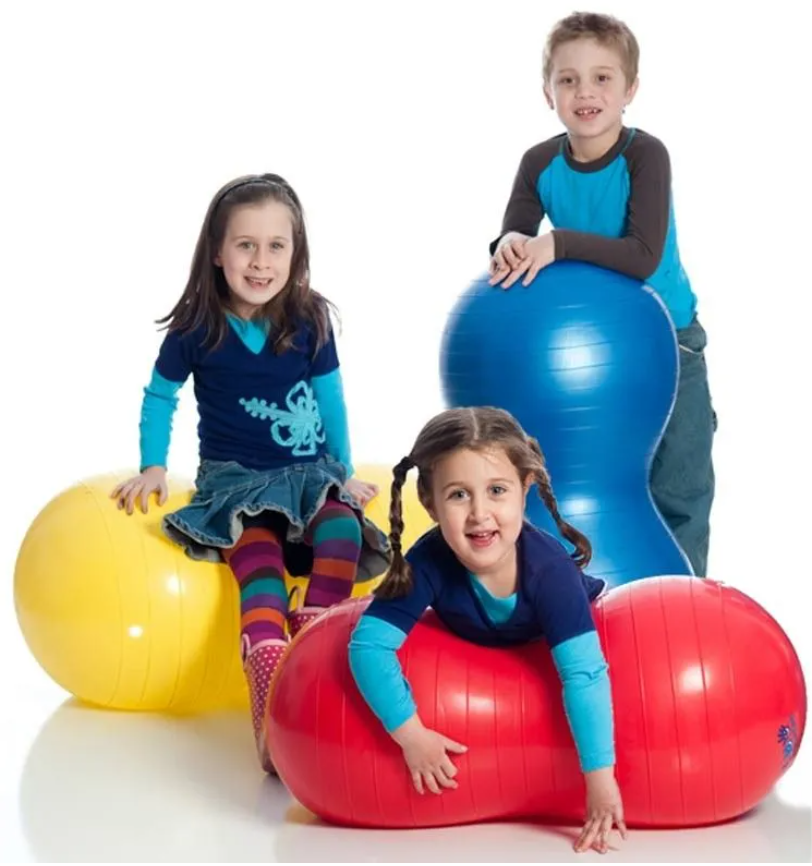 Three children over a white background sitting and standing with peanut shaped balance roll balls in red, yellow, and blue